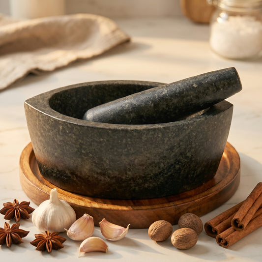 Boat shape stone mortar and pestle in black Hansraj stone on a table with whole spices around it