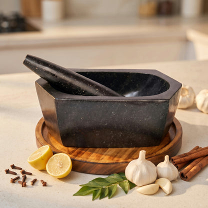 Hexagonal granite mortar and pestle on a table showing six sided black stone bowl and matching pestle